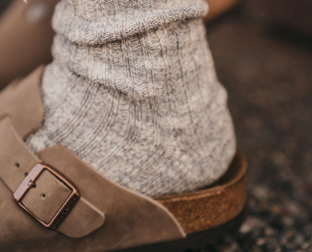 A foot with warm socks in a Birkenstock sandal.